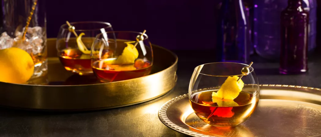 Glass of Courvoisier® Classic garnished with lemon peel on a steel tray