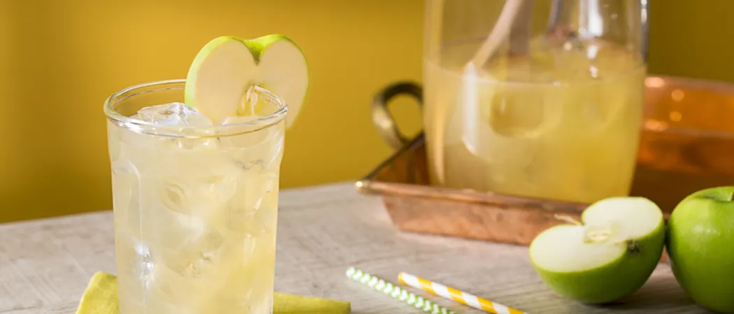A glass of Crisp Apple Ade garnished with green apple slice