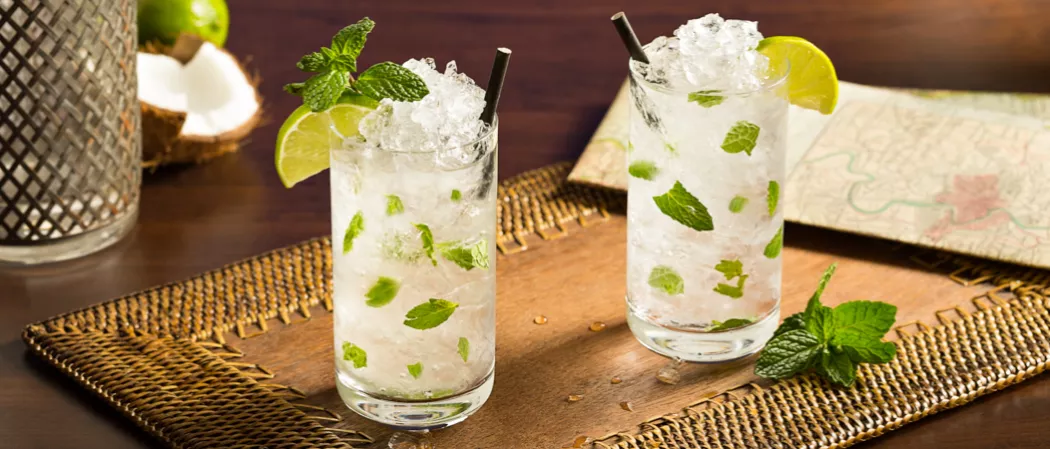 Two glasses of Classic Mojito garnished with mint leaves, lime wedge and straws