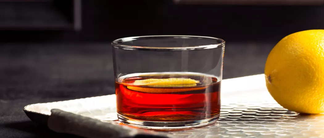 A glass of Hornitos® Black Barrel® Tequila Manhattan placed on the silver tray, garnished with orange peel.