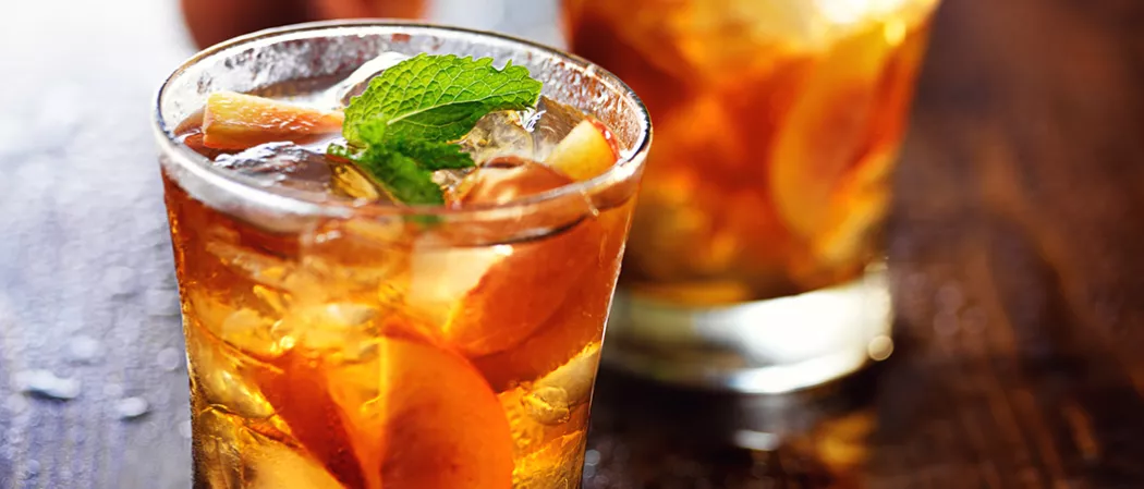 Glasses of Peach Mojito garnished with a mint sprig and a peach slice.