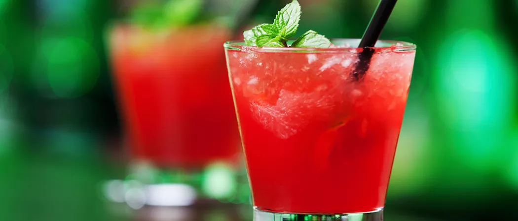Glass of Berry Burst with straws garnished with mint leaves