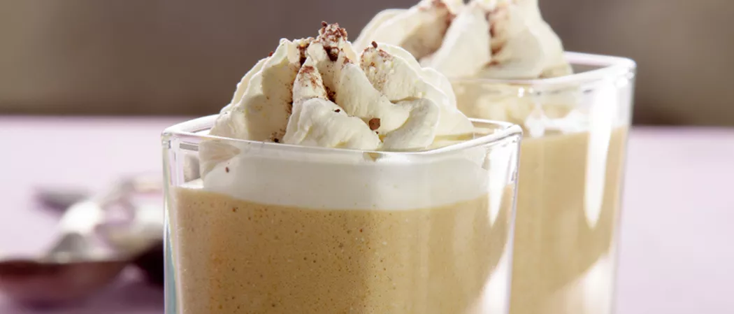 Two glasses of Buttery Nipple garnished with whipped cream