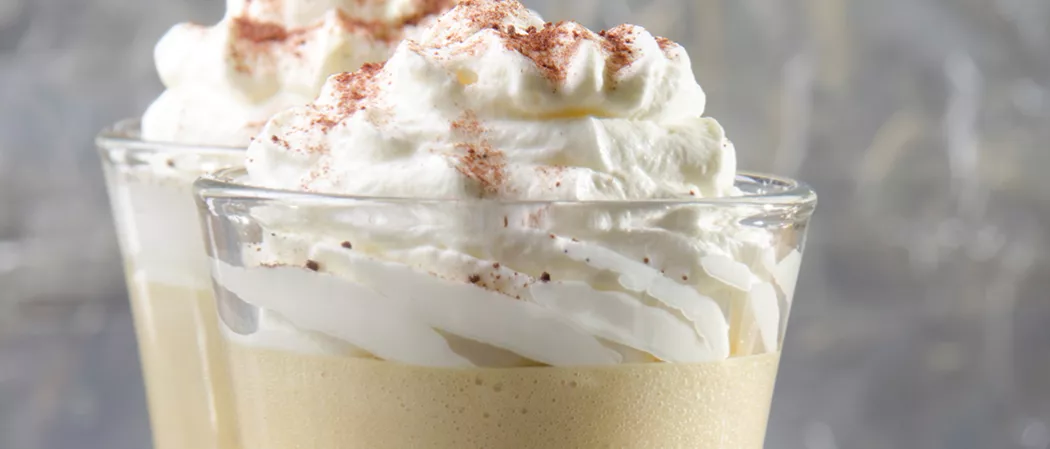 Two glasses of Buttery Nipple garnished with whipped cream
