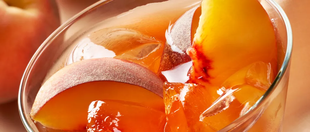Glass of Peach tea with peach slices and crushed ice