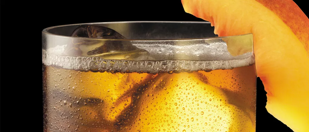 Glass of peach tea garnished with peach slice
