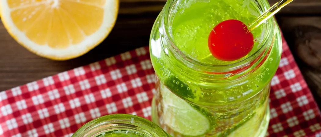 Jar of Midori® and Ginger garnished with a cherry.