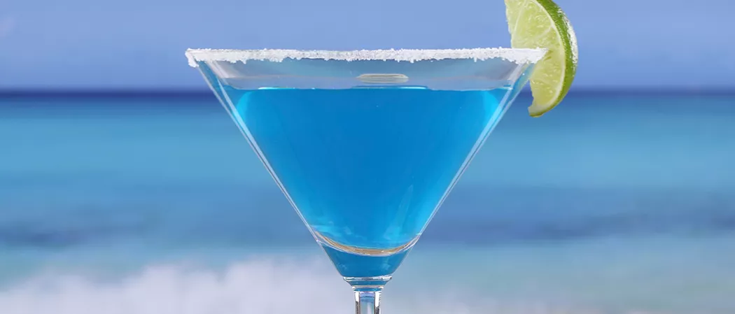 A cocktail glass of Sauza® Blue garnished with lemon slice with crushed sugar rim.