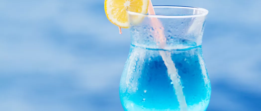 A tulip glass of Sauza® Blue garnished with lemon slice and straws in it.