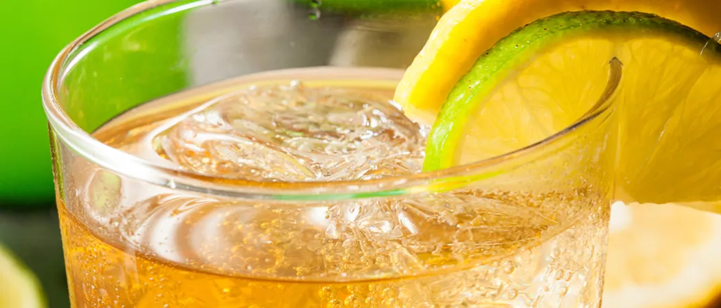 A Glass of Mexican mule garnished with yellow/green lemon slices on glass rim and ice cubes inside