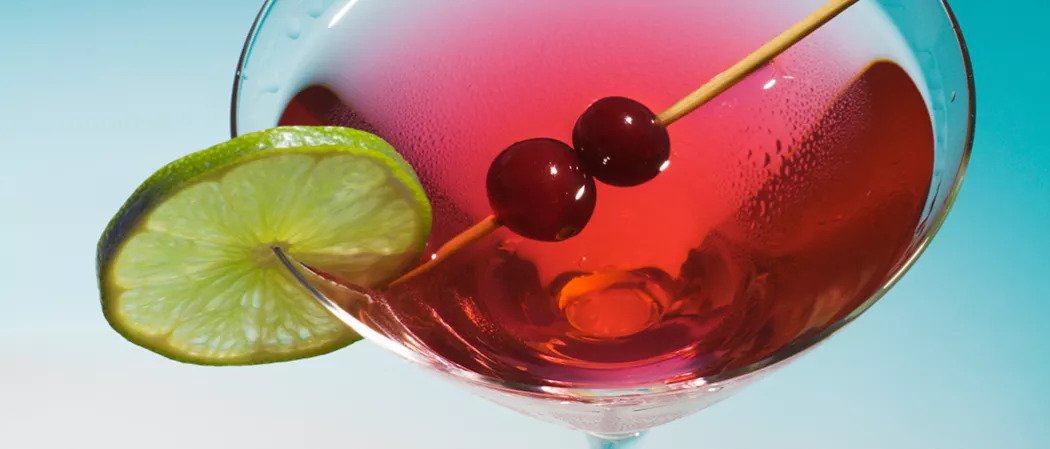 A Glass of Classic Cosmo garnished with cherries on toothpick and lime slice