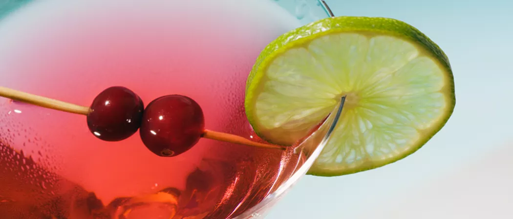  A Glass of Classic Cosmo garnished with cherries on toothpick and lime slice