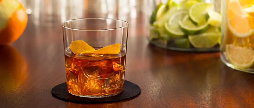 Glass of Old '97 garnished with orange peel on coaster