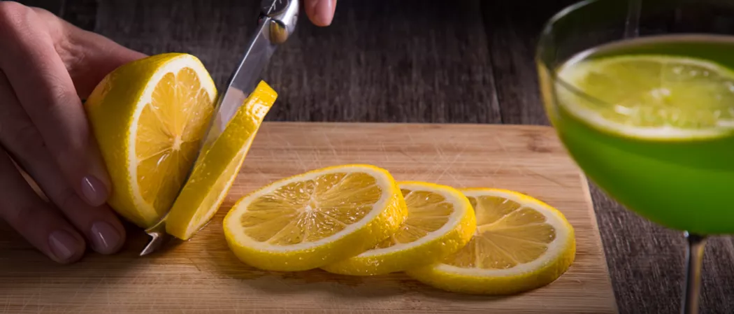 Person cutting lemon slices using knife 